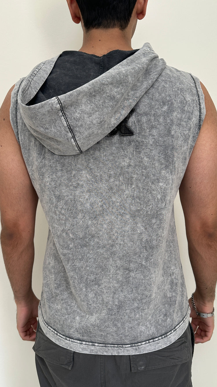 Person wearing a sleeveless gray hoodie against a plain background