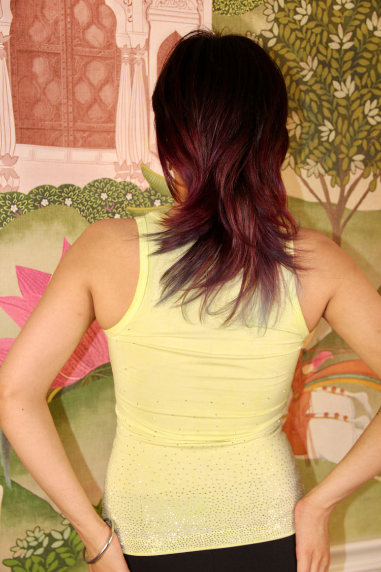 Model wearing a faded jade tank top against a floral wall.