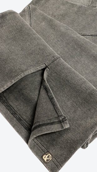 Close up of a dark grey skirt with a brand logo on a white background