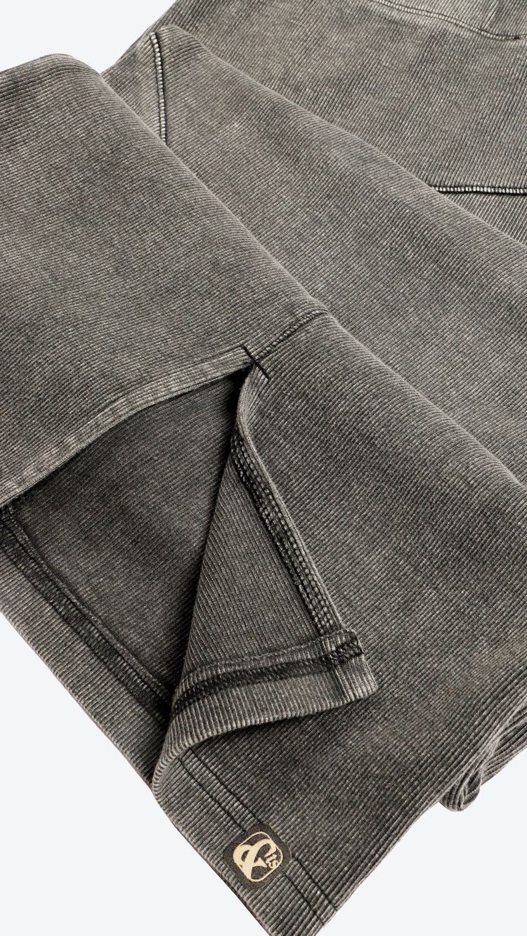Close up of a dark grey skirt with a brand logo on a white background