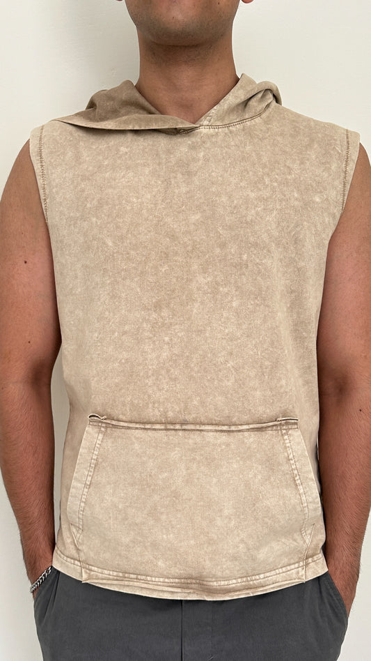 Beige sleeveless hoodie worn by a person on a plain background