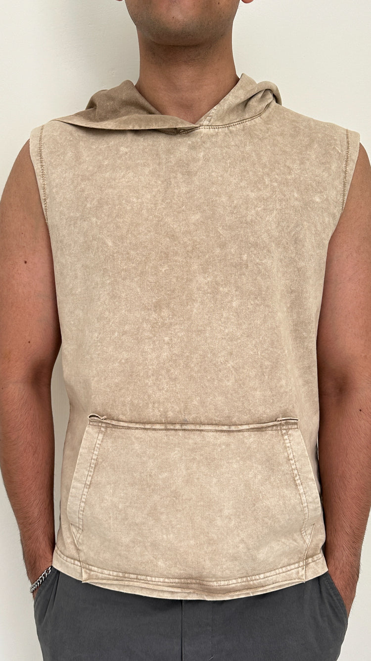 Beige sleeveless hoodie worn by a person on a plain background