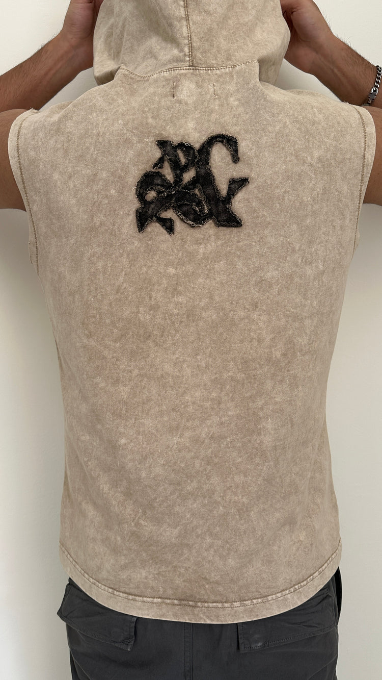 Beige sleeveless jacket with black logo on the back against a white background