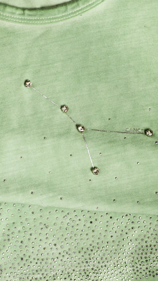 Close-up of a green tank top with a cancer constellation design.